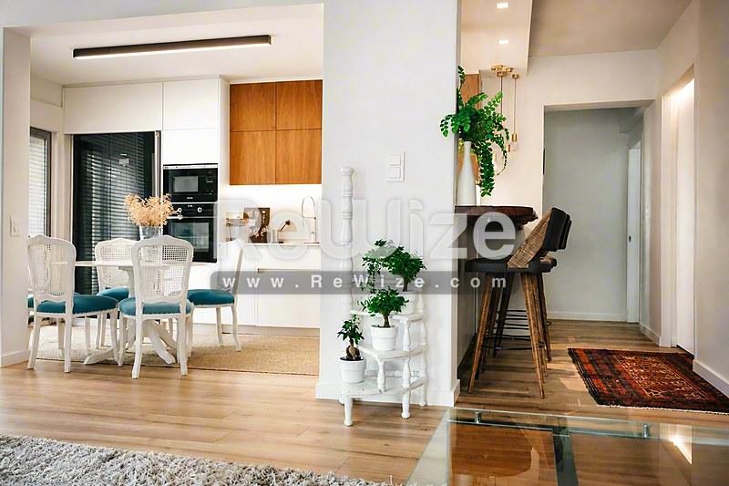 Ανοιχτόχωρος χώρος διαμερίσματος στη Χαλκιδική με ενιαίο σαλόνι, κουζίνα και τραπεζαρία με ξύλινα δάπεδα.