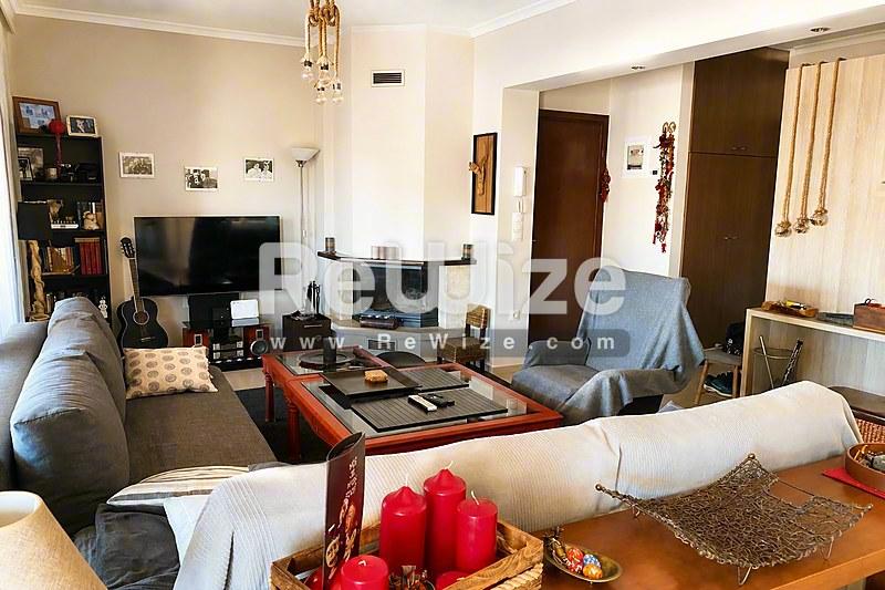 Φωτεινό σαλόνι διαμερίσματος στη Χαλκιδική με άνετες θέσεις καθίσματος και τζάκι.