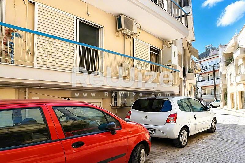 Πρόσοψη διαμερίσματος στη Χαλκιδική με μπαλκόνια και παρκαρισμένα αυτοκίνητα στο δρόμο.