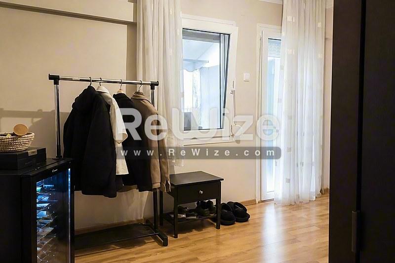 Φωτεινός διάδρομος διαμερίσματος στη Χαλκιδική με ξύλινο δάπεδο, κρεμάστρα και γυάλινες πόρτες.