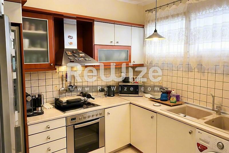 Συμπαγή κουζίνα διαμερίσματος στη Χαλκιδική με κρεμοζάντες ανοιχτού τόνου και βασικές συσκευές.