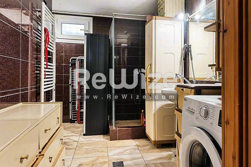 Σύγχρονο μπάνιο σε κατάστημα της Χαλκιδικής με μαύρα πλακάκια, λευκή νιπτήρα και ενσωματωμένες εγκαταστάσεις πλυσίματος.