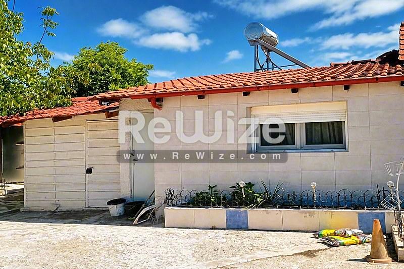 Μια γοητευτική εμπορική βιτρίνα στη Χαλκιδική με κόκκινα κεραμίδια και λευκά τοίχια.