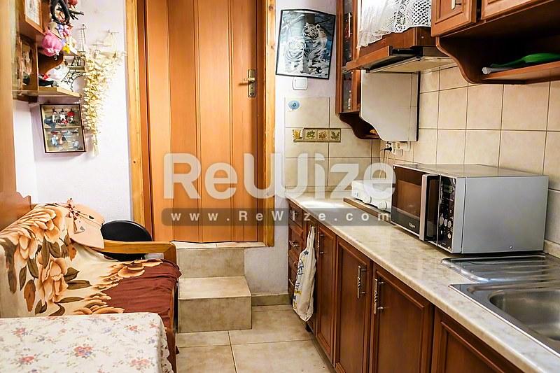 Συμπαγή κουζίνα σε κατάστημα της Χαλκιδικής με ξύλινα ντουλάπια και βασικές συσκευές.