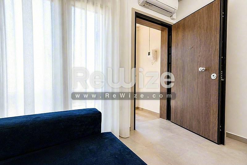 Σύγχρονη είσοδος διαμερίσματος στη Χαλκιδική με ξύλινη πόρτα, φωτεινό πάτωμα και σύγχρονες εγκαταστάσεις.