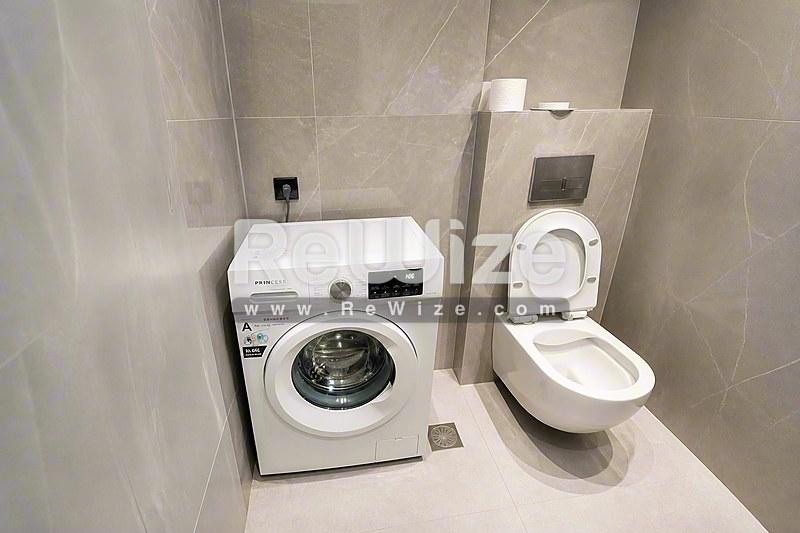 Σύγχρονο πλυντήριο διαμερίσματος στη Χαλκιδική με λευκό πλυντήριο ρούχων και ενσωματωμένη τουαλέτα.