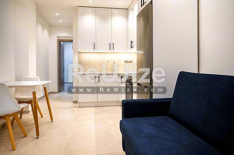 Ανοιχτός χώρος διαμερίσματος στη Χαλκιδική με σαλόνι, κουζίνα και σύγχρονο λευκό επιπλισμό.