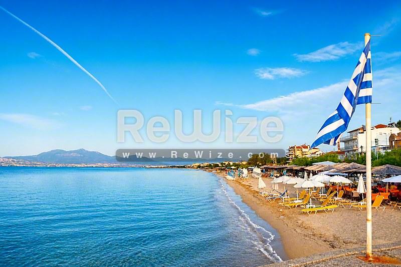 Μεζονέτα με θέα θάλασσας στη Χαλκιδική, αμμώδεις παραλίες και γαλάζια νερά με ελληνική σημαία.