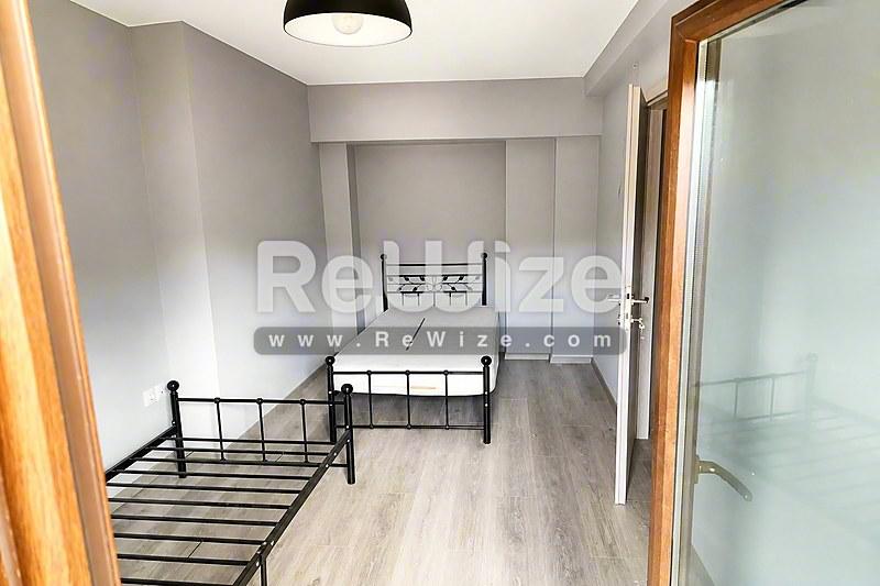 Φωτεινό υπνοδωμάτιο σε μεζονέτα στη Χαλκιδική με δύο μονά κρεβάτια, ξύλινο δάπεδο και σύγχρονους λευκούς τοίχους.