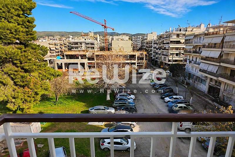 Θέα από μπαλκόνι διαμερίσματος στη Χαλκιδική με γειτονικά κτίρια, σταθμευμένα αυτοκίνητα και χόρους πρασίνου.