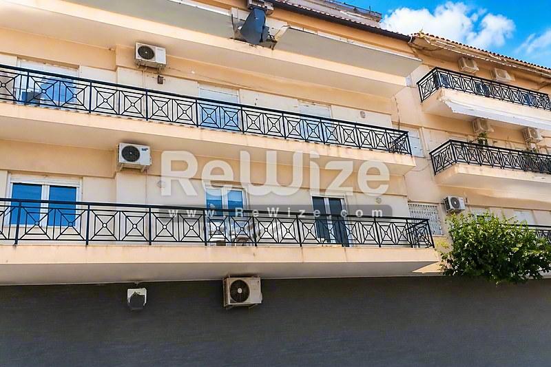 Σύγχρονη πολυκατοικία στη Χαλκιδική με διαμερίσματα, μπαλκόνια με μπλε κάγκελα και κλιματιστικά.
