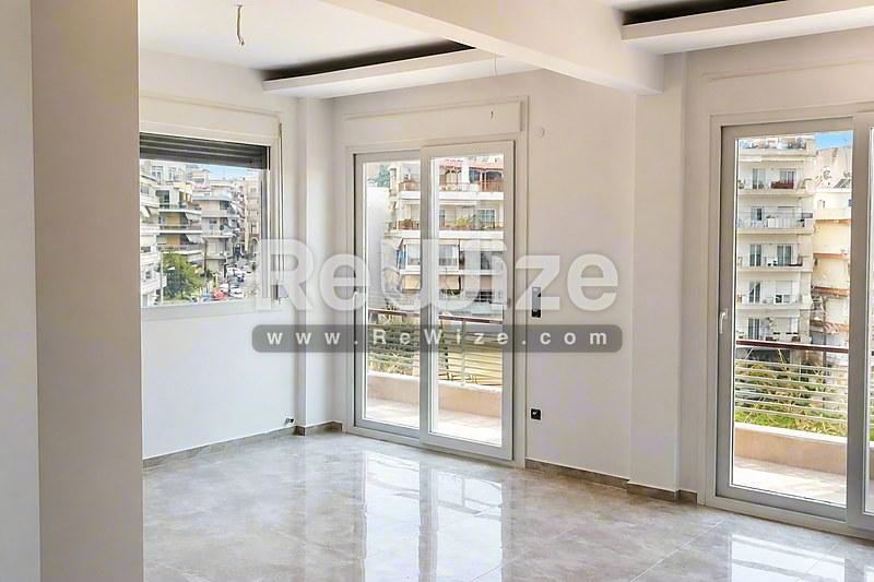 Φωτεινό σαλόνι διαμερίσματος στη Χαλκιδική με πολλές γυάλινες πόρτες και παράθυρα με θέα στην πόλη.
