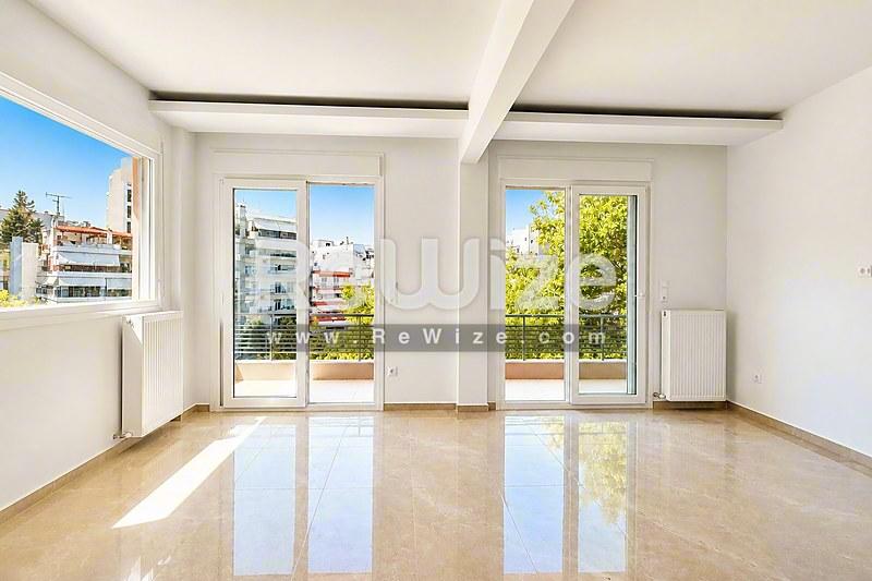 Φωτεινό σαλόνι διαμερίσματος στη Χαλκιδική με γυαλισμένο μάρμαρο και πανοραμικές γυάλινες πόρτες.