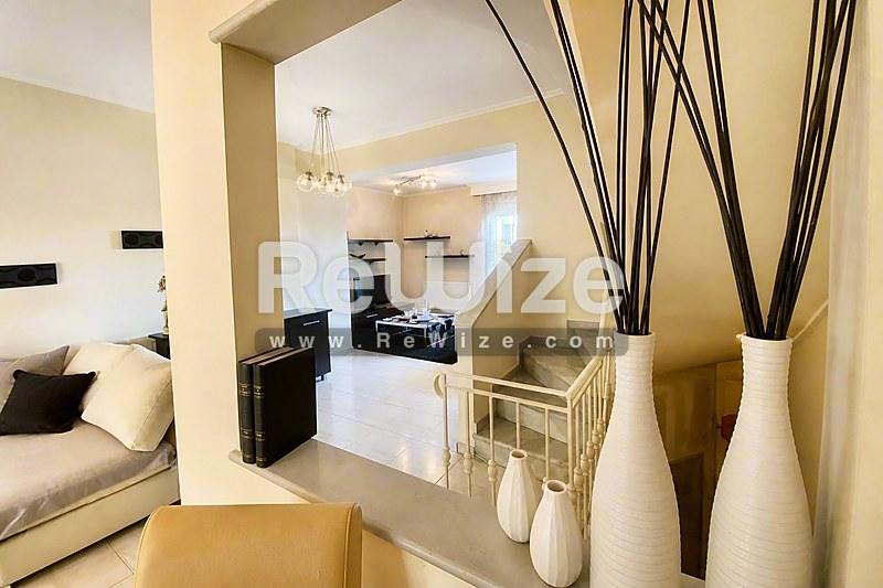 Σαλόνι σύγχρονης μεζονέτας στη Χαλκιδική με ανοιχτή κουζίνα και ελάχιστη διακόσμηση.