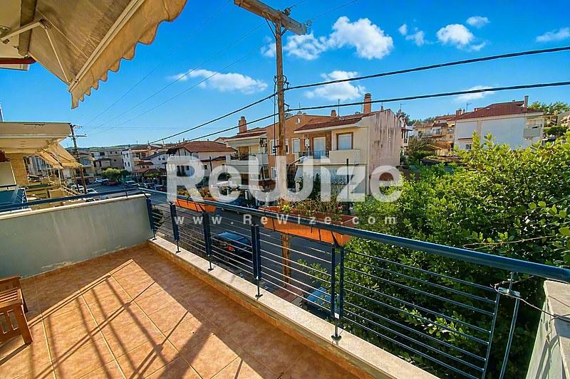 Ηλιόλουστη βεράντα μεζονέτας στη Χαλκιδική με θέα και σύγχρονες μαύρες κουπαστές.