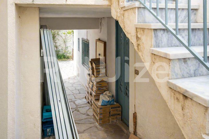 Είσοδος μονοκατοικίας στη Χαλκιδική με πλακόστρωτο δάπεδο και χώρο αποθήκευσης.