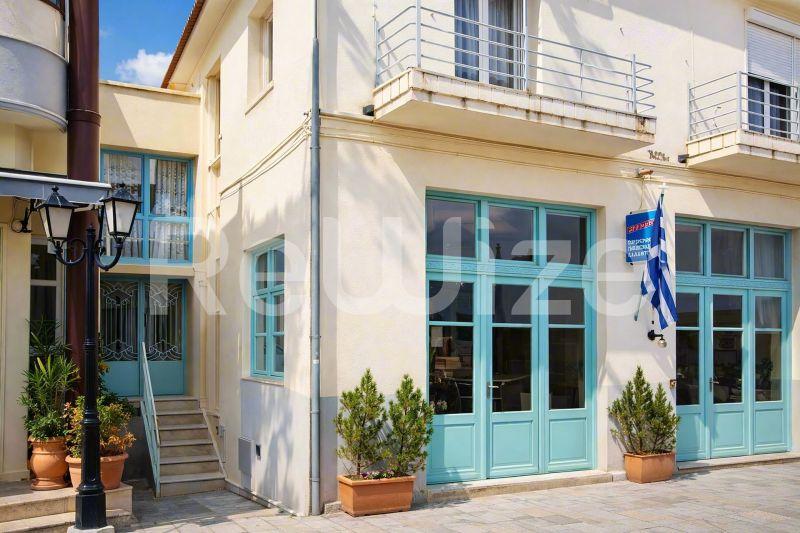 Όμορφη πρόσοψη μονοκατοικίας στη Χαλκιδική με τυρκουάζ διπλές πόρτες και λευκές τοίχους.