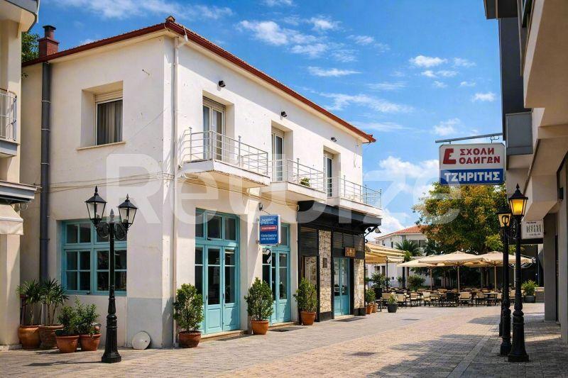 Όμορφη μονοκατοικία στη Χαλκιδική με μπλε παντζούρια και εμπορικό χώρο ισογείου, με μεσογειακή αρχιτεκτονική.