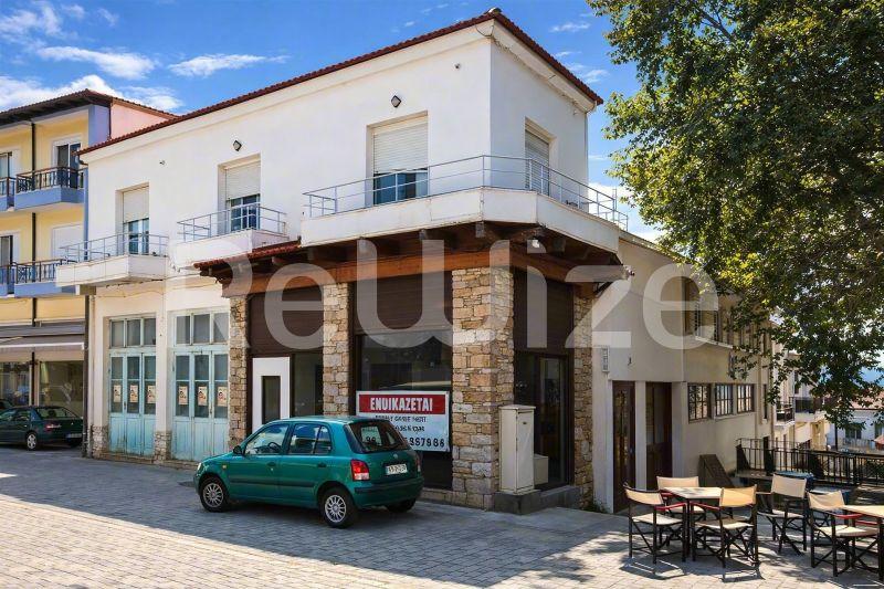 Σύγχρονη όψη μονοκατοικίας στη Χαλκιδική με λευκά τοιχώματα, ξύλινες λεπτομέρειες και χώρο καταστήματος.