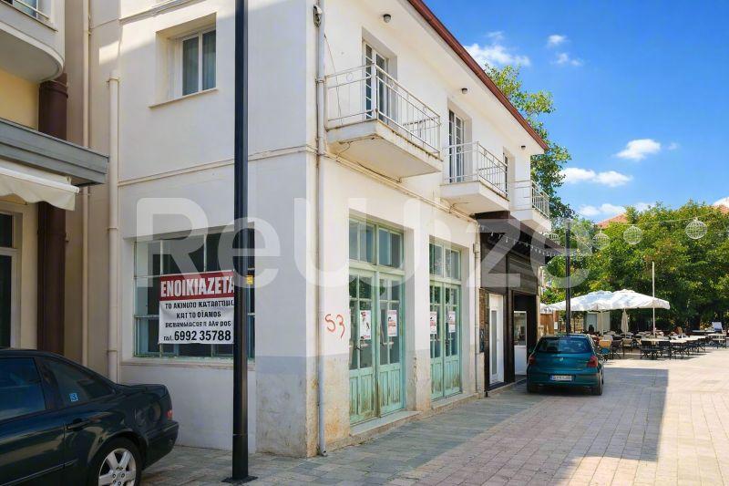 Πρόσοψη μονοκατοικίας στη Χαλκιδική με πράσινα παντζούρια, κατάστημα ισογείου και κατοικήσιμους ορόφους.