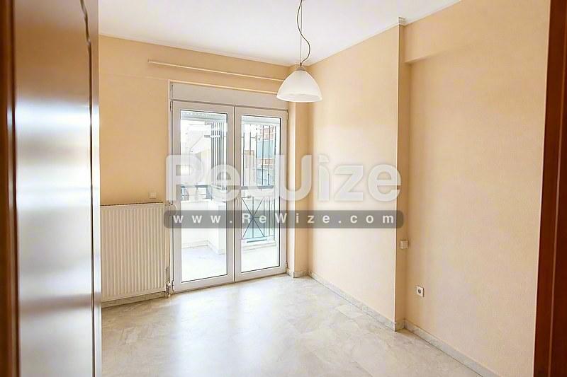 Φωτεινό σαλόνι διαμερίσματος στη Χαλκιδική με σύγχρονες λεπτομέρειες και γυάλινες πόρτες μπαλκόνι.