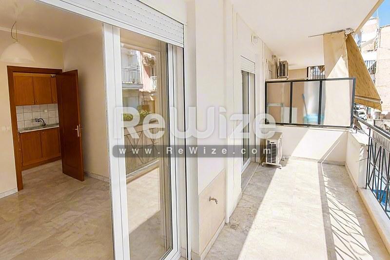 Φωτεινή βεράντα διαμερίσματος στη Χαλκιδική με συρόμενες γυάλινες πόρτες και μεταλλικές κάγκελες.