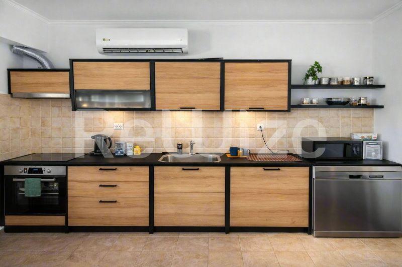 Σύγχρονη κουζίνα με ξύλινα ντουλάπια και συσκευές από ανοξείδωτο χάλυβα σε διαμέρισμα στη Χαλκιδική.