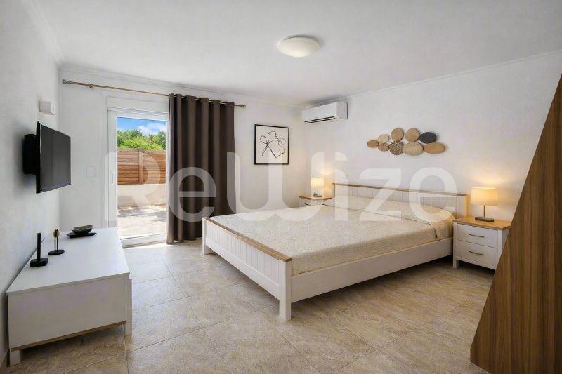 Просторна主寝室 διαμερίσματος στη Χαλκιδική με άνετο κρεβάτι, σύγχρονα έπιπλα και πρόσβαση σε ιδιωτική βεράντα.