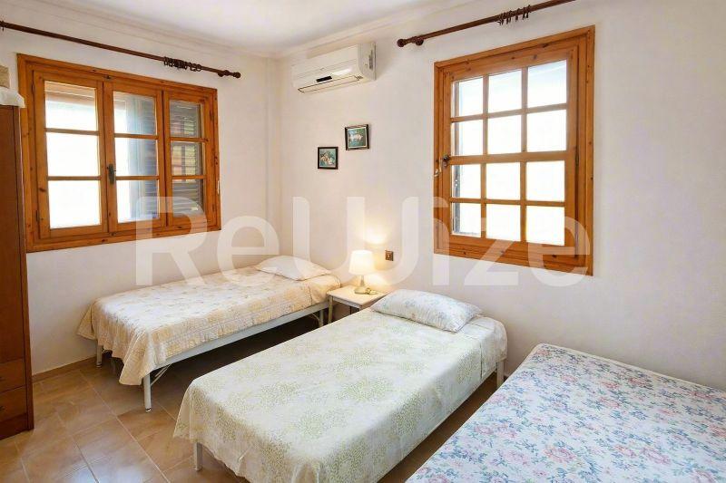 Φωτεινό υπνοδωμάτιο με τρία μονά κρεβάτια σε μονοκατοικία στη Χαλκιδική, με ξύλινα παράθυρα και απλή διακόσμηση.