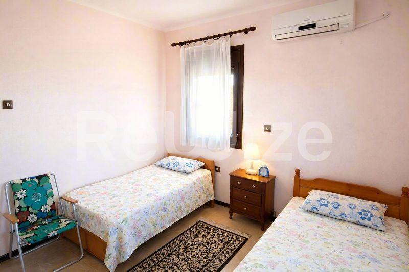Φωτεινό υπνοδωμάτιο σε μονοκατοικία στη Χαλκιδική με δύο μονά κρεβάτια και ξύλινα έπιπλα.