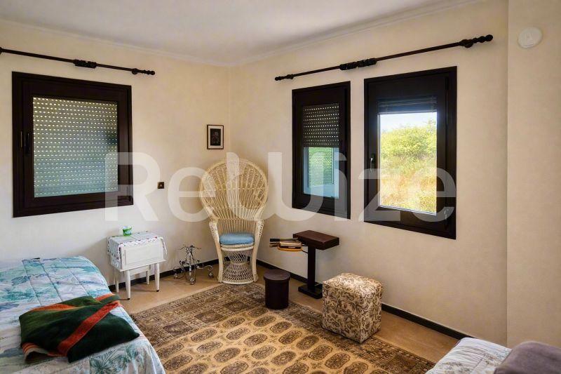Φωτεινό υπνοδωμάτιο σε μονοκατοικία στη Χαλκιδική με δύο κρεβάτια και μεγάλα παράθυρα.