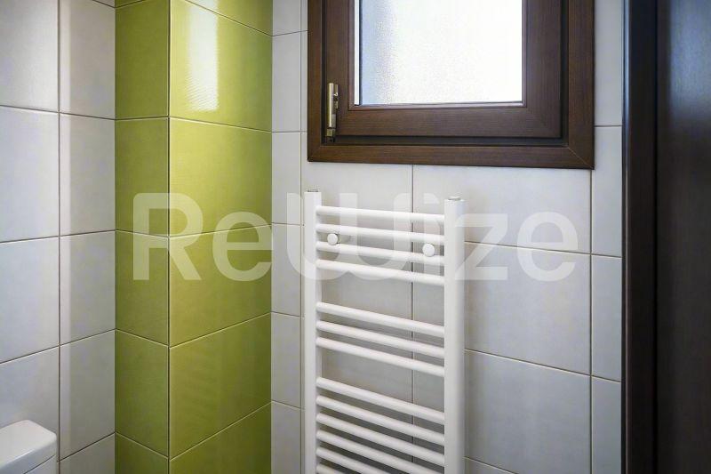 Σύγχρονο μπάνιο μεζονέτας στη Χαλκιδική με πράσινα πλακάκια, λευκό θερμαινόμενο καλοριφέρ και σύγχρονες εγκαταστάσεις.