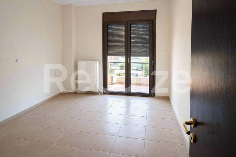 Φωτεινό υπνοδωμάτιο μεζονέτας στη Χαλκιδική με πλακάκια και πρόσβαση σε ιδιωτικό μπαλκόνι.