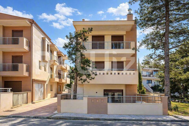 Σύγχρονη μεζονέτα στη Χαλκιδική με τριώροφη κτερίδα σε χρώμα τερακότα, μπαλκόνια και υπόγειο γκαράζ.