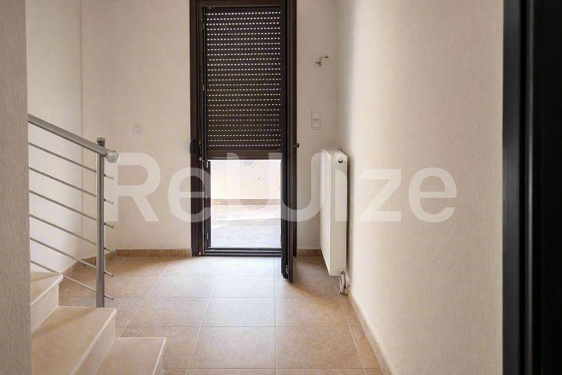 Φωτεινό διάδρομο εισόδου μεζονέτας στη Χαλκιδική με σύγχρονο πλακάκι και μεταλλικές σχάρες.