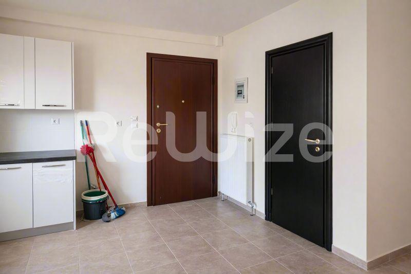Φωτεινή είσοδος μεζονέτας στη Χαλκιδική με πλακάκια, λευκά ντουλάπια κουζίνας και δύο εσωτερικές πόρτες.