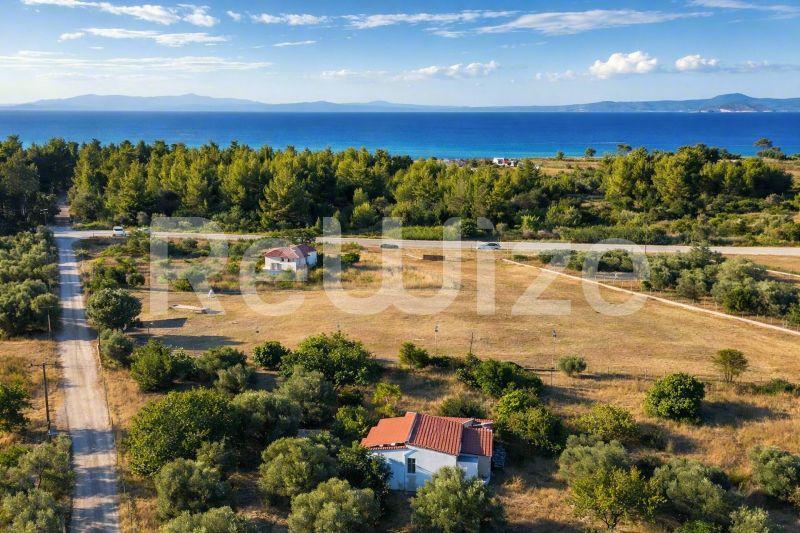 Αεροφωτογραφία μονοκατοικίας με κόκκινη στέγη περιτριγυρισμένης από πράσινο χώρο και δέντρα στη Χαλκιδική, με θέα στη θάλασσα.