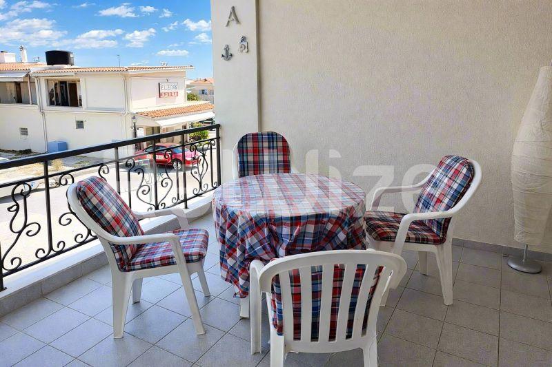 Ηλιόλουστο μπαλκόνι μεζονέτας στη Χαλκιδική με τραπέζι, καρέκλες και θέα προς την πόλη.