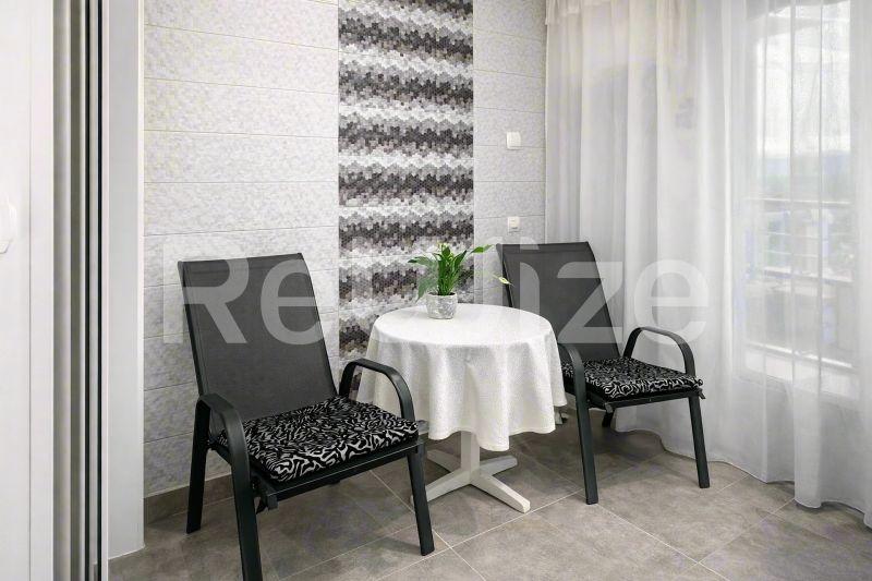 Κομψό μπαλκόνι μεζονέτας στη Χαλκιδική με δύο μαύρες καρέκλες ξαπλώνης και μικρό στρογγυλό τραπέζι με λευκό τραπεζόμαντιλο.