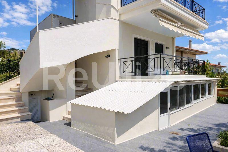 Σύγχρονη μεζονέτα στη Χαλκιδική με λευκή καμπύλη αρχιτεκτονική, πολλαπλά επίπεδα και συρόμενη τέντα.