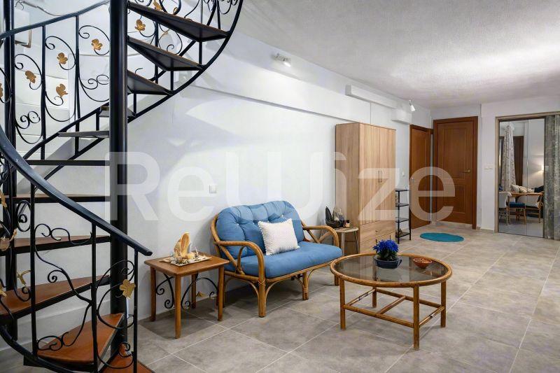 Σύγχρονη σπειροειδής σκάλα σε μεζονέτα της Χαλκιδικής με άνετο καθιστικό.