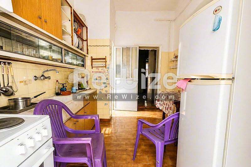 Συμπαγή κουζίνα διαμερίσματος στη Χαλκιδική με ξύλινα ντουλάπια, vintage συσκευές και μωβ καρέκλες.