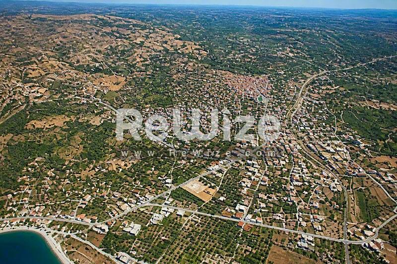 Εναέρια άποψη οικοπέδου στη Χαλκιδική με πράσινη βλάστηση και γειτονικές κατοικίες.