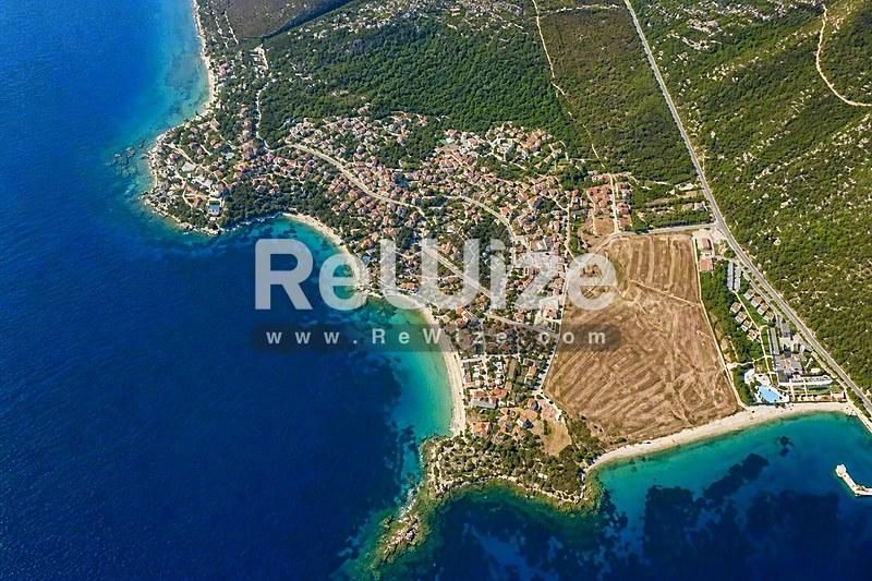 Αεροφωτογραφία οικοπέδου στη Χαλκιδική με άμεση πρόσβαση σε παραλία, περιτριγυρισμένο από πράσινο και γαλάζια νερά.