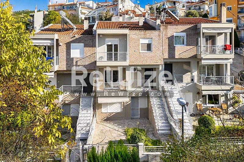 Σύγχρονη μεζονέτα στη Χαλκιδική με σοφιστικέ αρχιτεκτονική, λευκή πέτρινη όψη και πολλαπλά επίπεδα.
