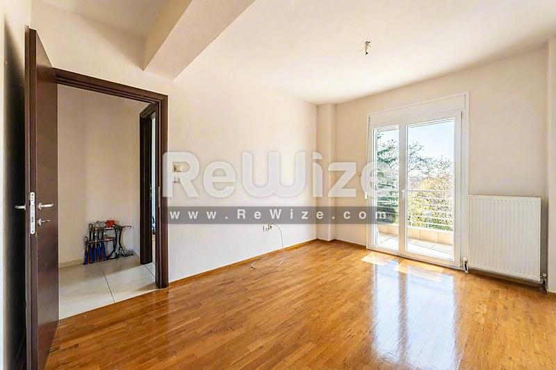 Φωτεινό σαλόνι μεζονέτας στη Χαλκιδική με ξύλινα δάπεδα, λευκά τοίχα και πρόσβαση σε μπαλκόνι.