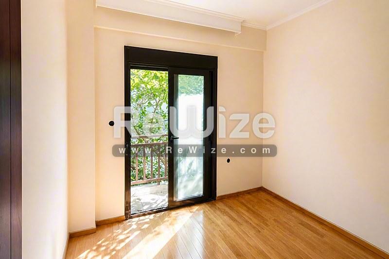 Φωτεινό υπνοδωμάτιο σε διαμέρισμα στη Χαλκιδική με ξύλινα πατώματα και πρόσβαση σε μπαλκόνι.