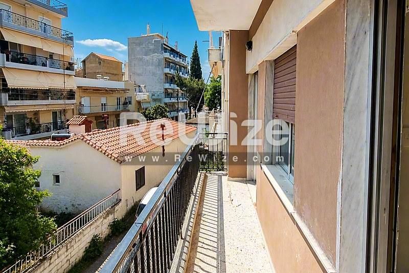 Ηλιόλουστο μπαλκόνι διαμερίσματος στη Χαλκιδική με θέα σε μεσογειακές στέγες και γειτονικά κτίρια.