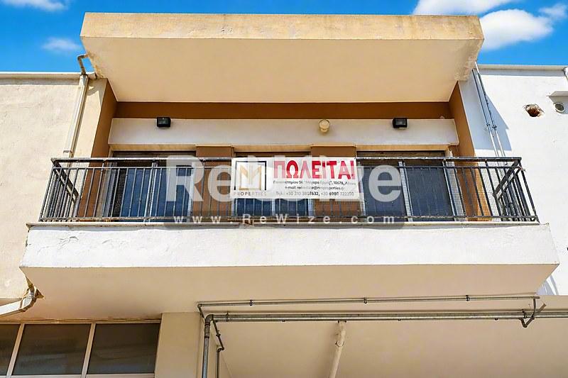 Σύγχρονη πρόσοψη διαμερίσματος στη Χαλκιδική με μπαλκόνι και κατάστημα ισογείου.