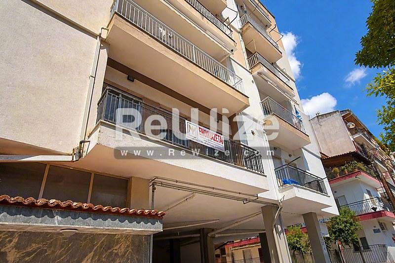 Σύγχρονη πολυκατοικία στη Χαλκιδική με πολλαπλά μπαλκόνια και κατάστημα ισογείου.